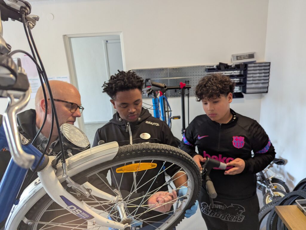 En man som visar yngre kring cykellagning